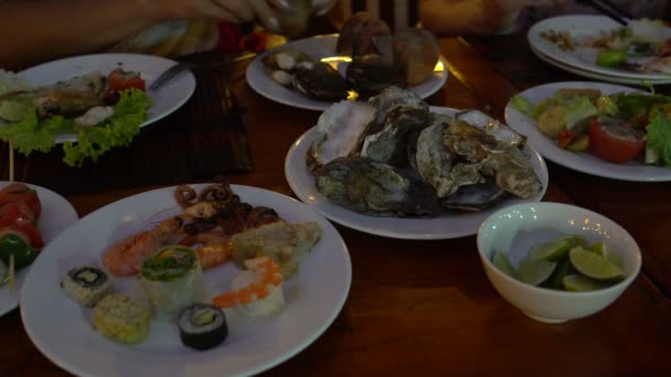 Mesa con platos de mariscos. Las manos de mujer toman la ostra — Vídeo de stock