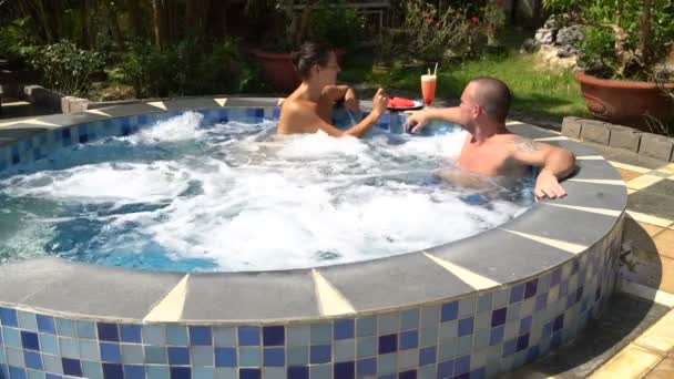 Eine Frau füttert einen Mann mit Wassermelone im Whirlpool — Stockvideo