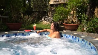 Açık havada bir kokteyl içme Jakuzi bir kadında.
