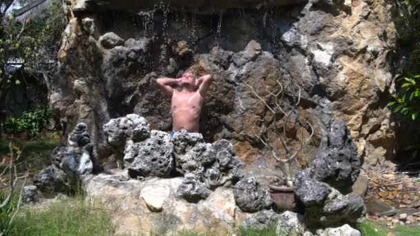 Man koelt onder een waterval — Stockvideo