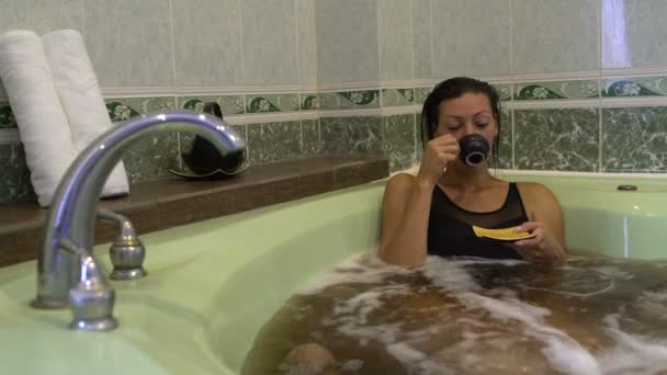 Ein Mädchen liegt im Whirlpool mit Kräutern und Teetrinkern — Stockvideo