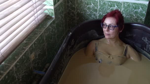 Жінка лежить у грязьовій ванні — стокове відео