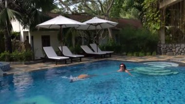 Kadın açık hava havuzunda yüzün. Kız dalışlar ve su altında yüzüyor