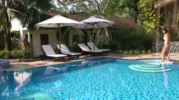 Uma mulher entra na piscina e nada. — Vídeo de Stock