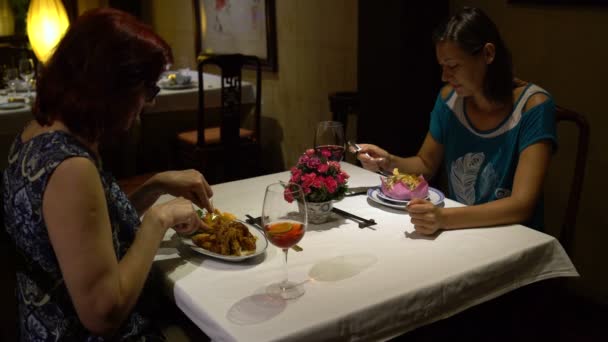 Жінки сидять за столом у ресторані, їдять і розмовляють — стокове відео