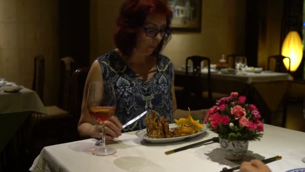 Vrouw zitten aan een tafel in het restaurant eten, praten, chokaetsja een glas en het drinken van rode wijn — Stockvideo