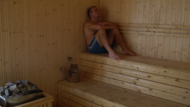 Un hombre tomando el sol en la sauna sentado en el dosel — Vídeo de stock