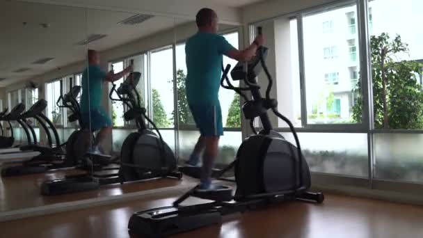 Mannen var i hallen för en elliptisk motionscykel — Stockvideo