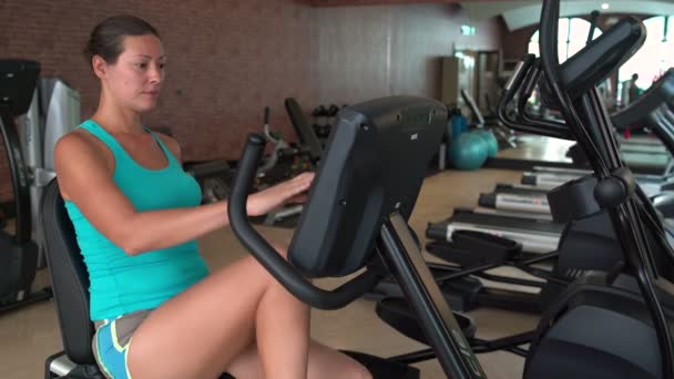 Een vrouw op de sportschool op een hometrainer deals — Stockvideo