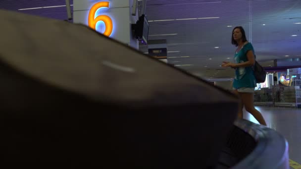 À l'aéroport, il y a une femme dans la salle d'attente des bagages à la bande transporteuse . — Video