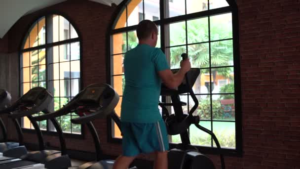 Dans le gymnase, l'homme a un exerciseur elliptique — Video