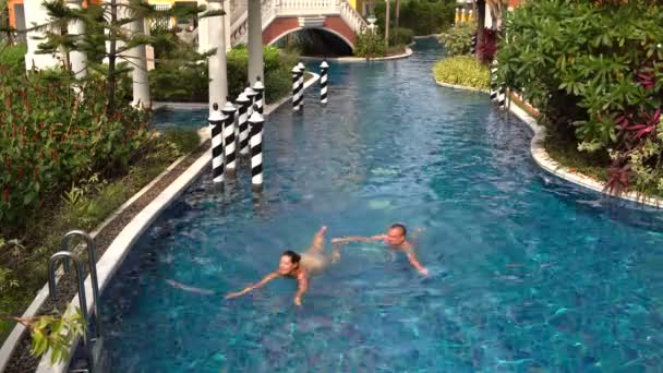 Um homem e uma mulher nadando na piscina, nadando até as escadas e fora da piscina — Vídeo de Stock