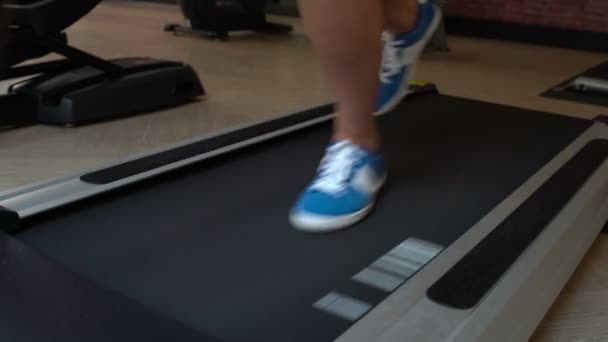 Les pieds des femmes courent sur le tapis roulant à la salle de gym — Video