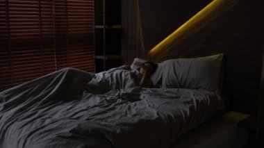 Kız yatakta uyuyor. Alarm çalar ve kadın uyanır ve esneme