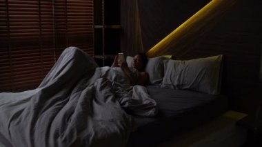 Yatakta bir kadın senin Smartphone ile yatıyordu.