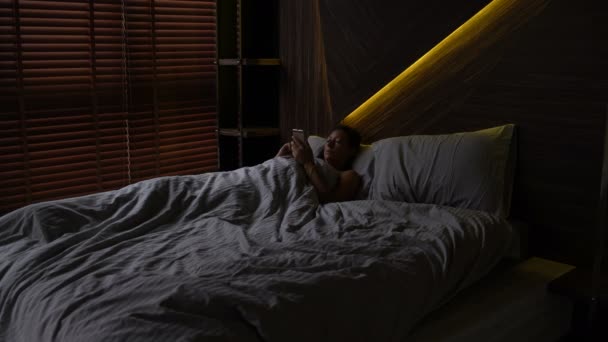 Κορίτσι με ένα Smartphone που βρίσκεται στο κρεβάτι — Αρχείο Βίντεο
