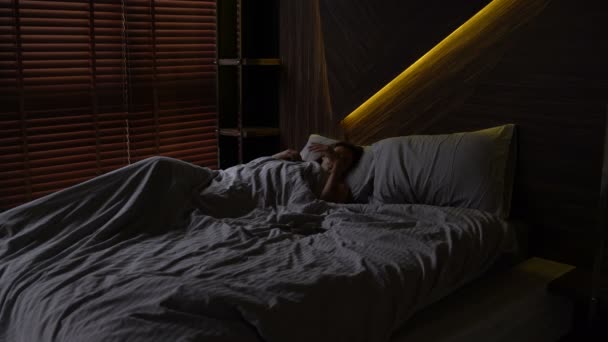 A lány alszik az ágyban. Riasztás megy le, és a nő felébred, és stretching — Stock videók