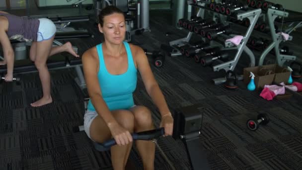 Girl in the gym has been rowing Simulator — Stock Video