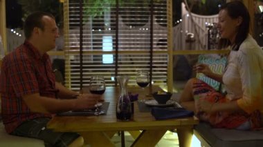 Restoranda, bir masada oturan bir kadın olan bir adam gözlük tıklatması ve kırmızı şarap içmek