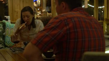 Çift oturur ve de restoran yiyor. Bir erkek bir kadın bir kadeh kırmızı şarap bir sürahi üzerinden dökülen.