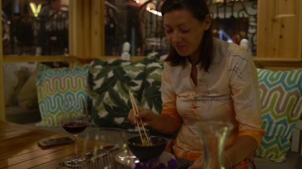 Γυναίκα τρώει σε ένα εστιατόριο και επικοινωνεί — Αρχείο Βίντεο
