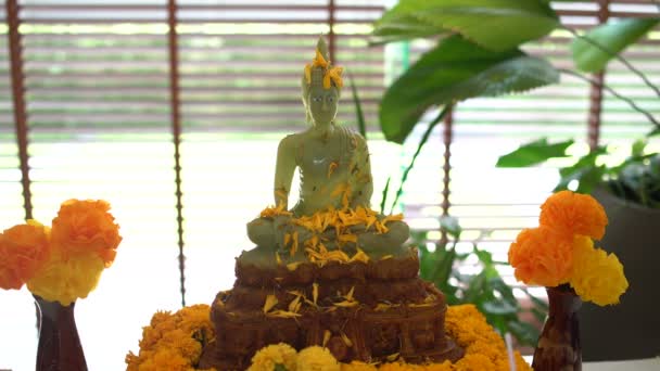 Buddhistischer Liederkran. weibliche Hand gießt eine Buddha-Statue mit Wasser und Jasminblättern — Stockvideo