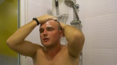 Bir adamın kafasını duşta yıkar.