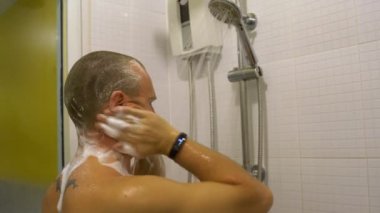 Adam kafasını şampuan ile lathers ve duşta durulama