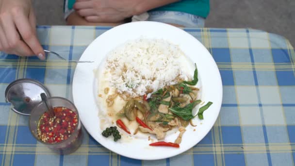 Уличная еда. Женщина ест рис с тушеными овощами за столом — стоковое видео