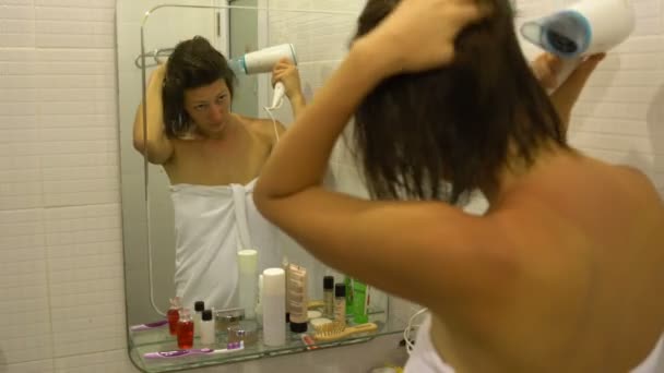 Žena v ručníku vysouší vlasy Fén před zrcadlem v koupelně