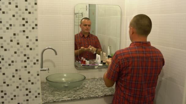 Man Puts Moisturizer His Face Front Mirror Bathroom — Stock Video