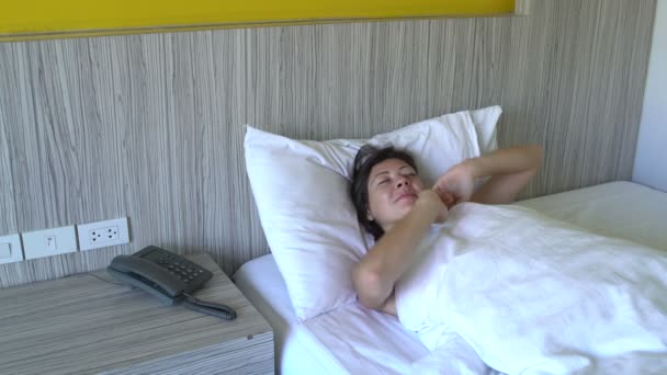 Bir kadın yatakta yatıyor ve esneme — Stok video