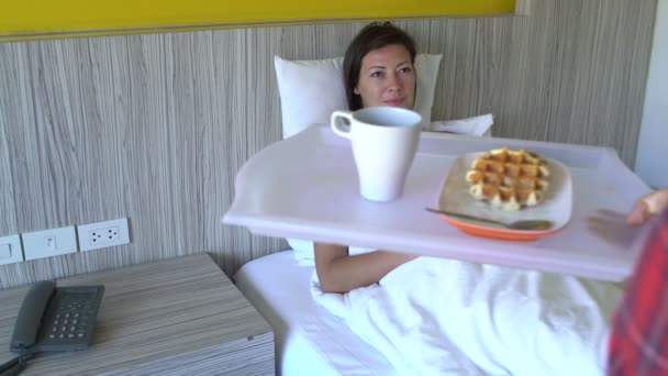 Bir erkek bir kadın waffle getirecek ve kahve bir tepsi yanına oturur ve onu öper — Stok video