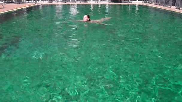 Uma mulher banha-se na piscina exterior — Vídeo de Stock