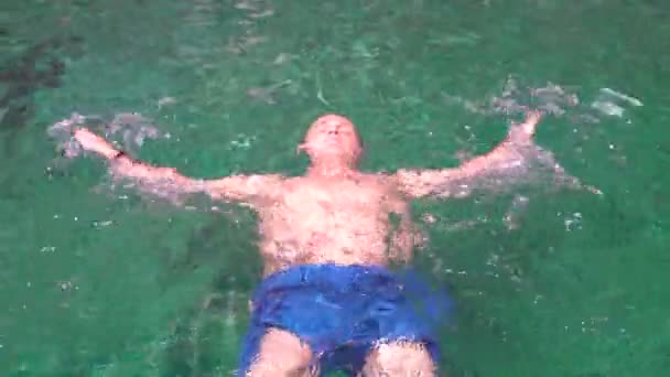 Чоловік плаває на спині у відкритому басейні — стокове відео