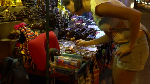 Uma mulher tira dinheiro e compra um íman numa loja de recordações na rua. — Vídeo de Stock