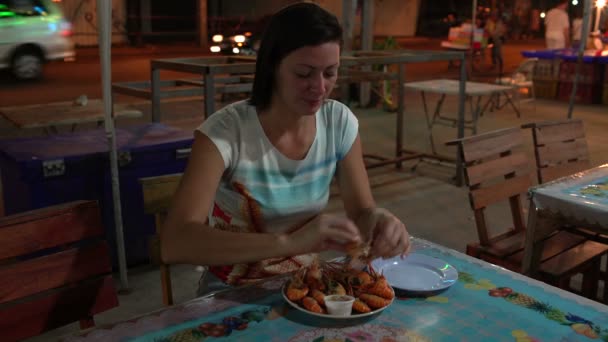 Vrouw eet de garnalen in café op straat — Stockvideo