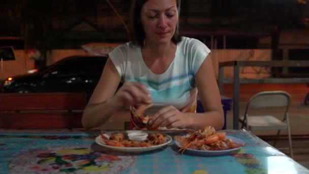 Comida de rua. Uma mulher está molhando um camarão em um molho e comendo . — Vídeo de Stock