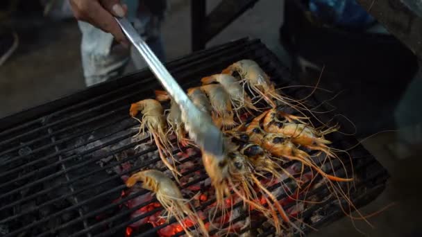 Krewetki królewskie są smażone na grill. Mężczyzna ręka przewraca krewetki przy użyciu pęsety — Wideo stockowe