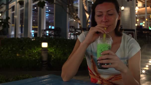Žena pije čaj bubliny při sezení u stolu na ulici. — Stock video