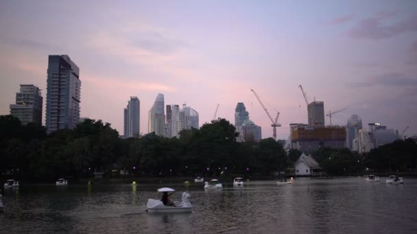 在摩天大楼和建筑起重机背景下的船公园里的湖 — 图库视频影像