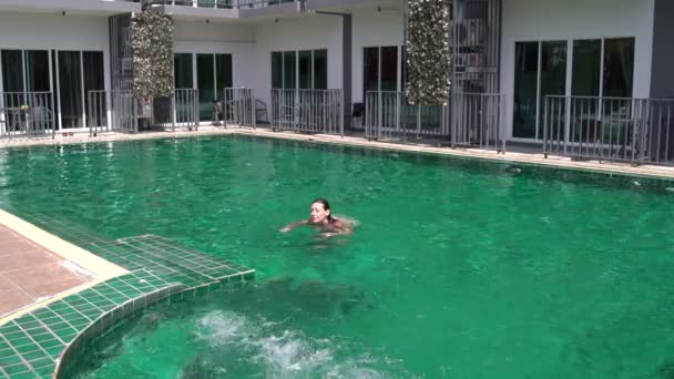 Woman swims up to the steps and out of the pool — Stock Video