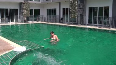 Bir kadın havuzdan gelir ve bir havlu ile sildi