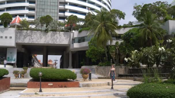 Una mujer camina por la calle desde el edificio del hotel — Vídeos de Stock