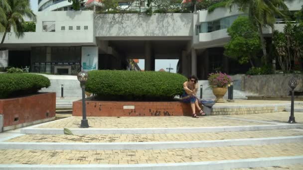 Frau sitzt auf den Stufen vor dem Hotel — Stockvideo