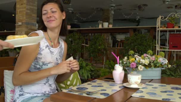 Een vrouw zit aan een tafel in een restaurant. De ober brengt khao phat — Stockvideo