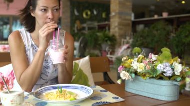 Bir restoran dışında bir masada oturan bir milkshake içme kadın