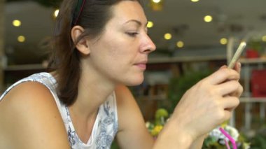 Bir restoranda bir milkshake içme kadın ve bir akıllı telefon sahiptir