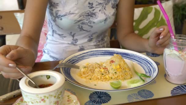 Een dames hand giet khao phat pikante saus met chili zitten aan een tafel in een restaurant — Stockvideo