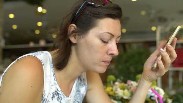 Woman eating in a restaurant and enjoys a Smartphone — Stock Video